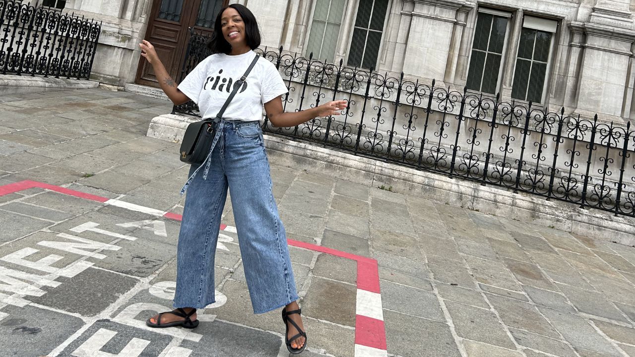 Kleidi Jeen wearing a white tee and jeans standing in front of the Paris Hotel de Ville
