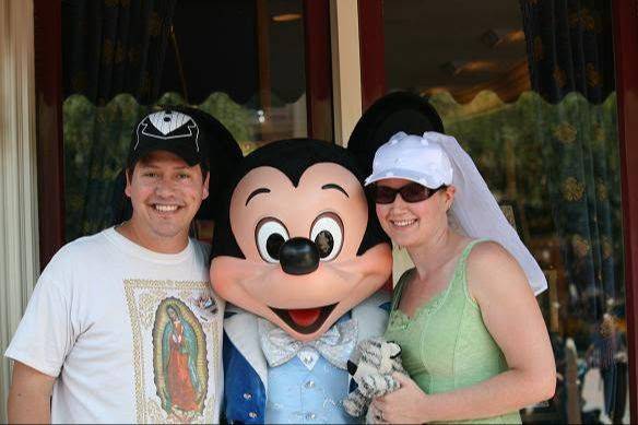 Brent and Amethyst at Disneyland with bride and groom hats on standing with Mickey.