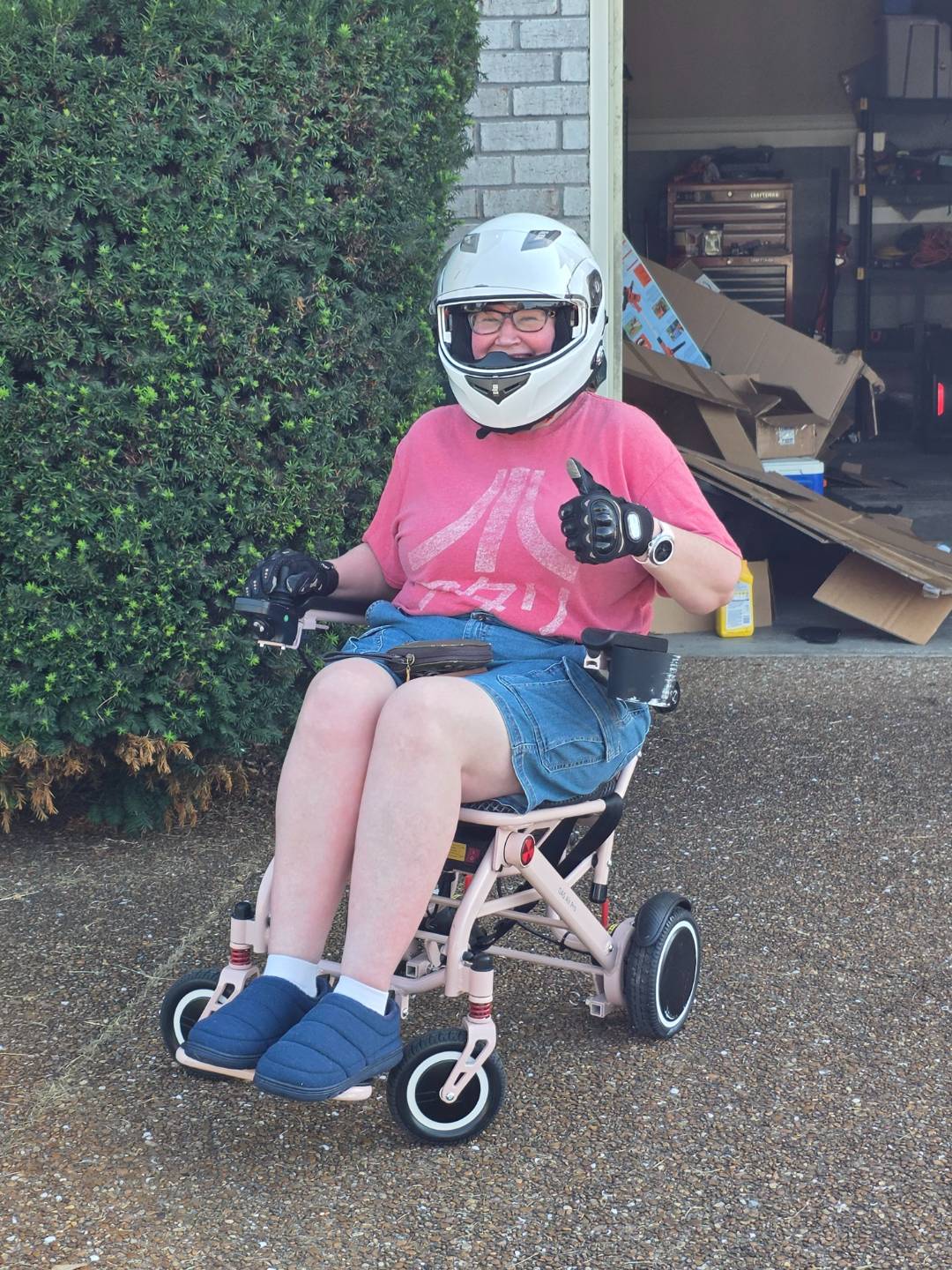 Amethyst Mahoney in a wheelchair with her motorcycle helmet on giving a thumbs up.