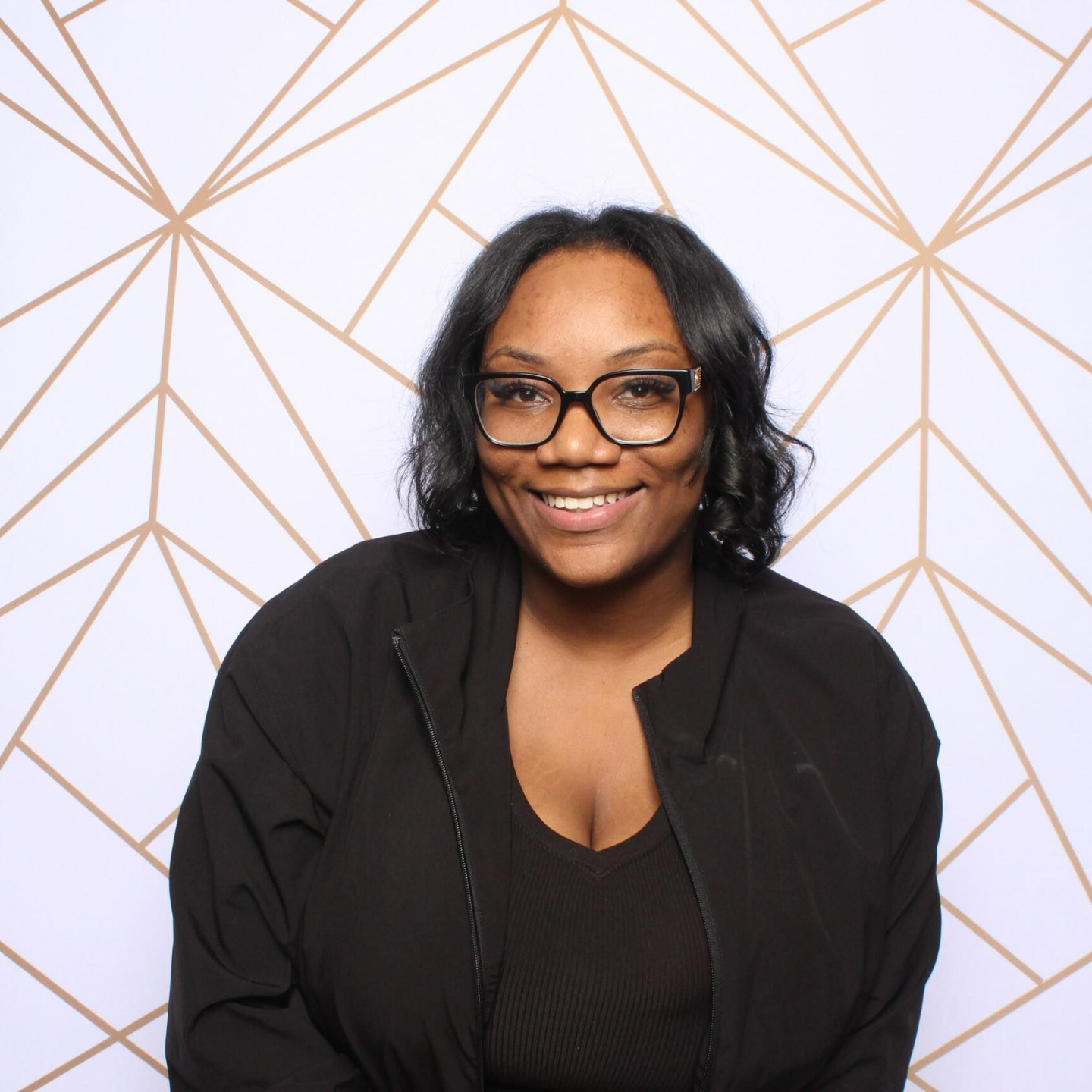 Picture of a woman smiling infront of a gold and white backdrop