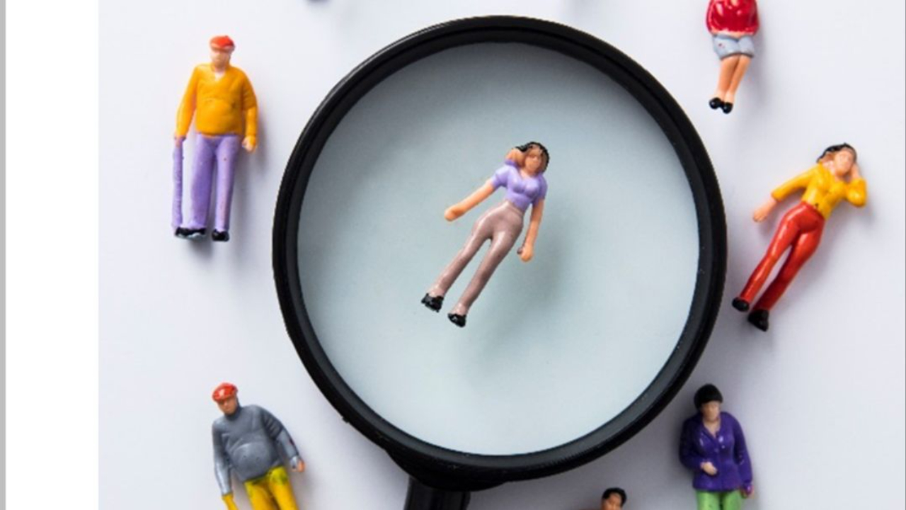 Magnifying glass highlighting one person among a team, symbolising the clarity and focus an EOS Integrator brings to frustrated leadership teams.