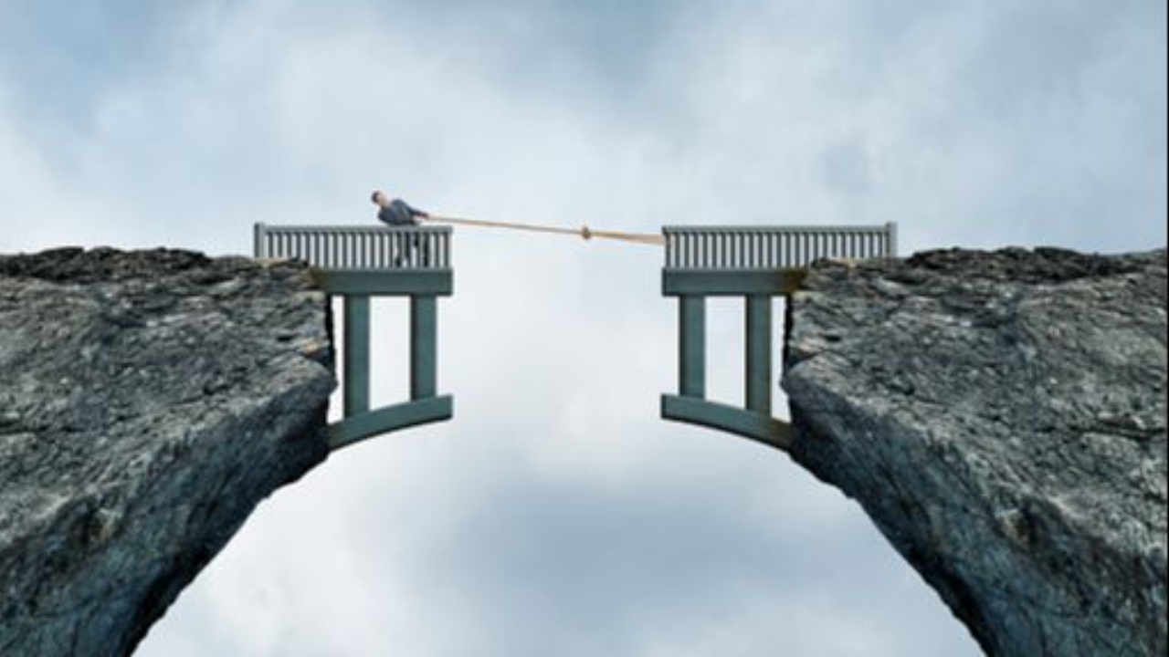 A conceptual image of a businessman on a bridge spanning a deep mountain chasm, physically using a rope to pull the two disconnected halves of the bridge together. This represents the Integrator Talent Gap in an EOS business, where the Integrator bridges the gap between high-level vision and operational execution with Independent Executives.
