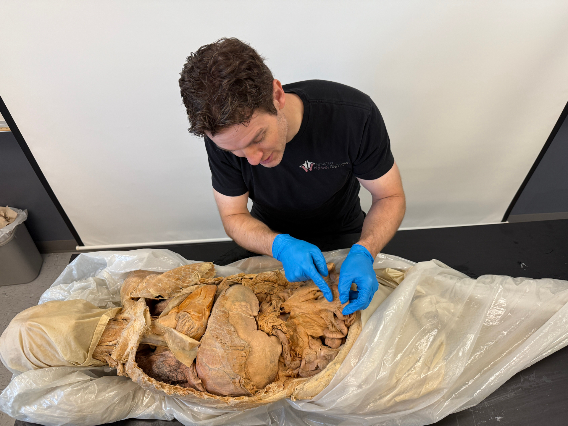 Jonathan Bennion of the Institute of Human Anatomy points to dissected human abdominal organs, including the stomach, liver, and intestines, during a cadaver lab demonstration.