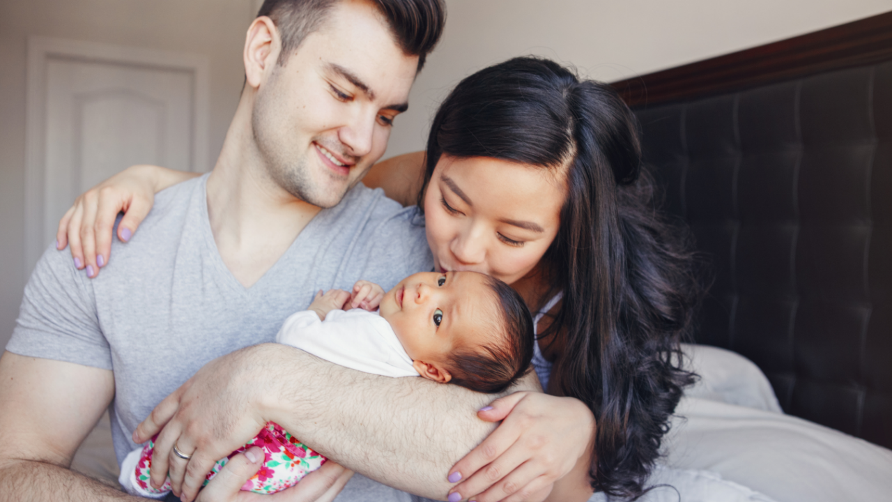 Young parents lovingly holding and bonding with their newborn baby during a calm connection moment at home.
