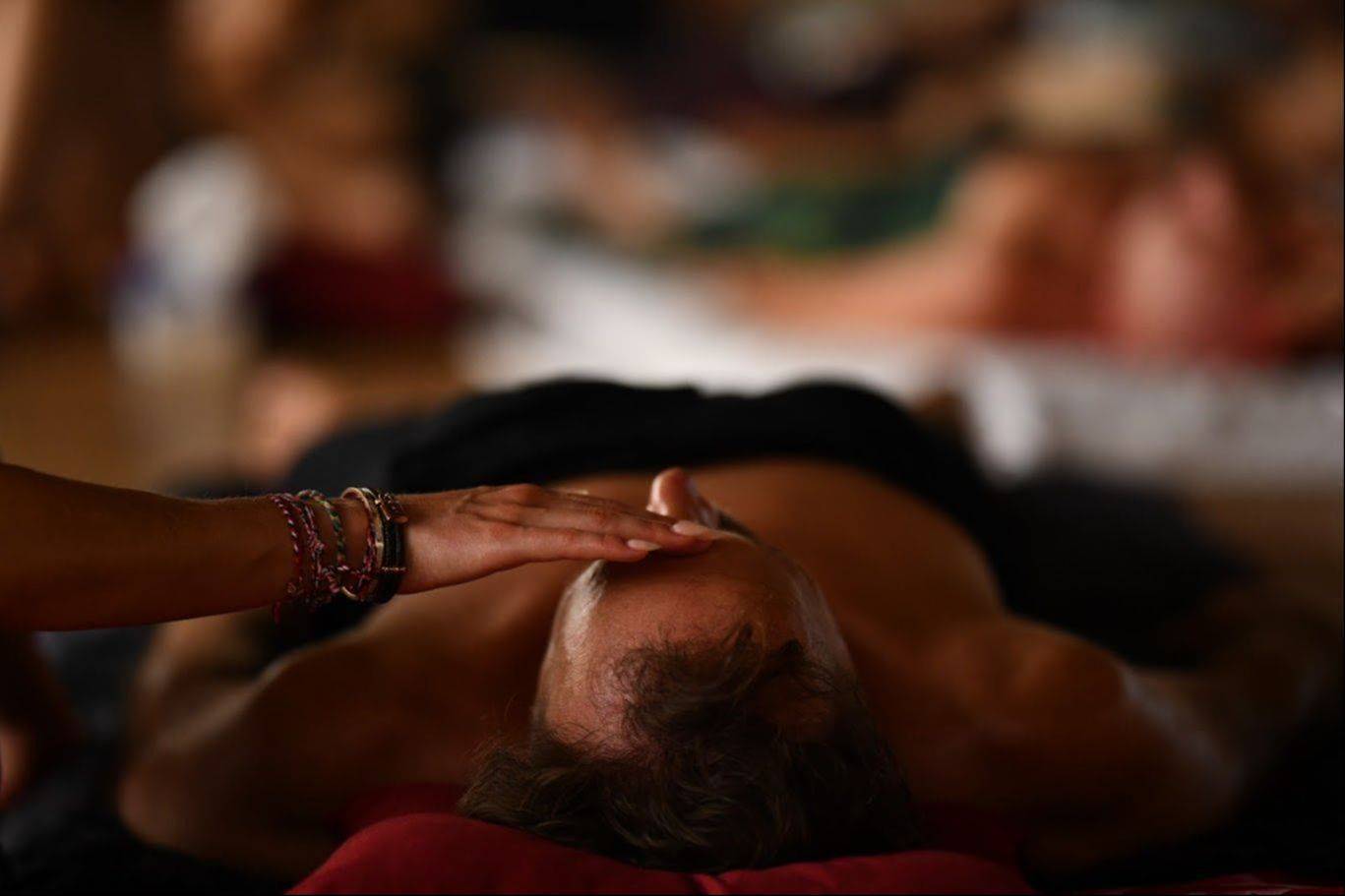 A practitioner's hand resting on a receiver's forehead during a Tantra massage