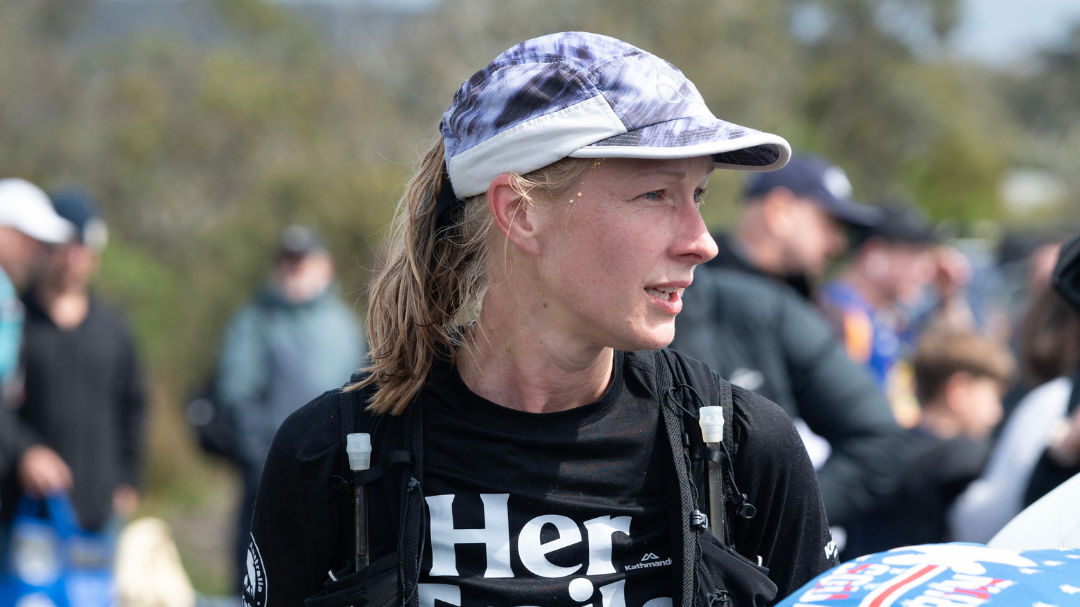 Female ultramarathon runner managing GI distress during a trail race, highlighting gut health strategies for women