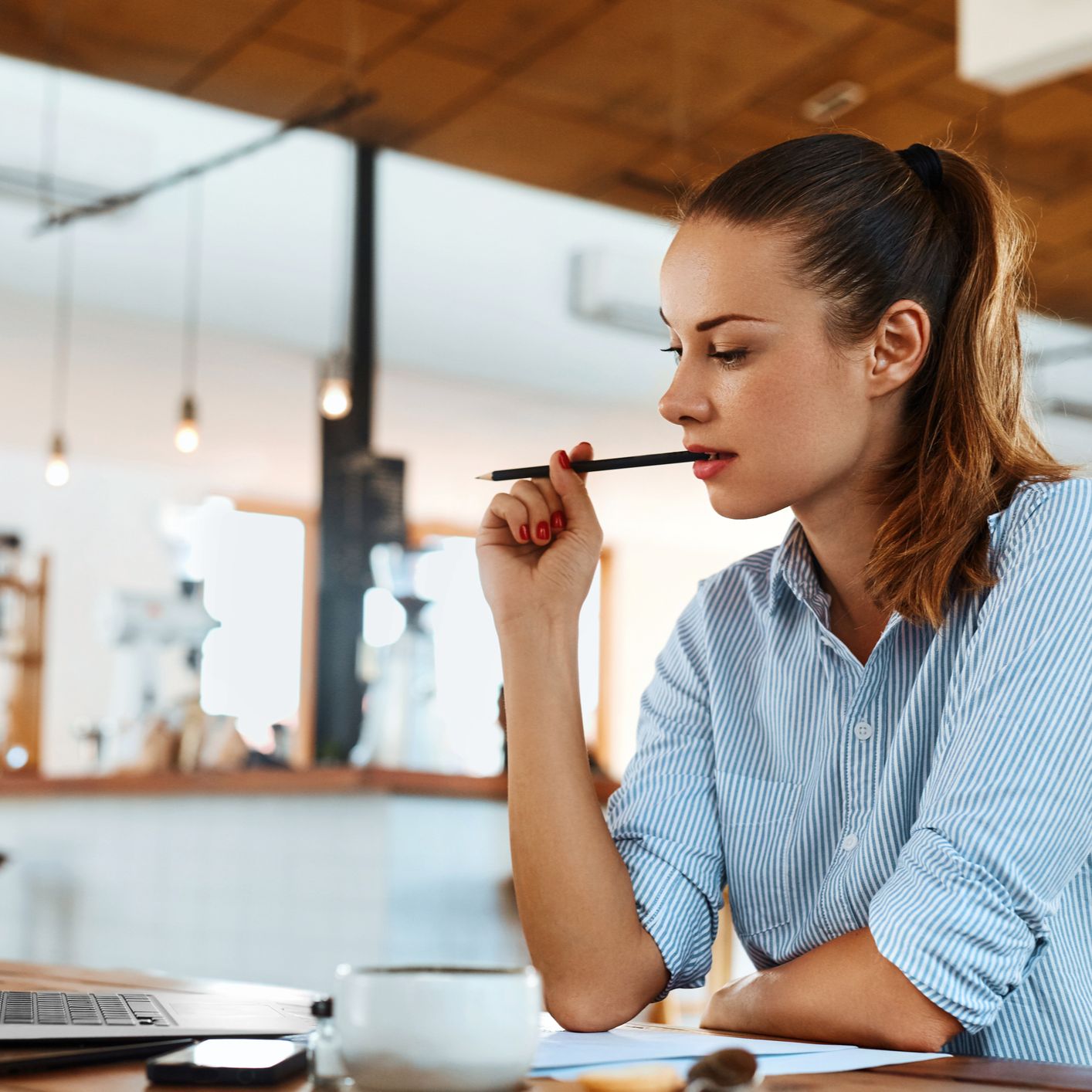 A woman sitting at a desk with her laptop, thinking about how to change careers and wanting to develop a job search strategy because she's been feeling stuck in her current role.