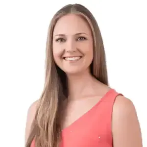 Career clarity coach, Theresa White,  wearing a sleeveless coral top, smiles while looking at the camera, exuding the confidence of a career clarity 