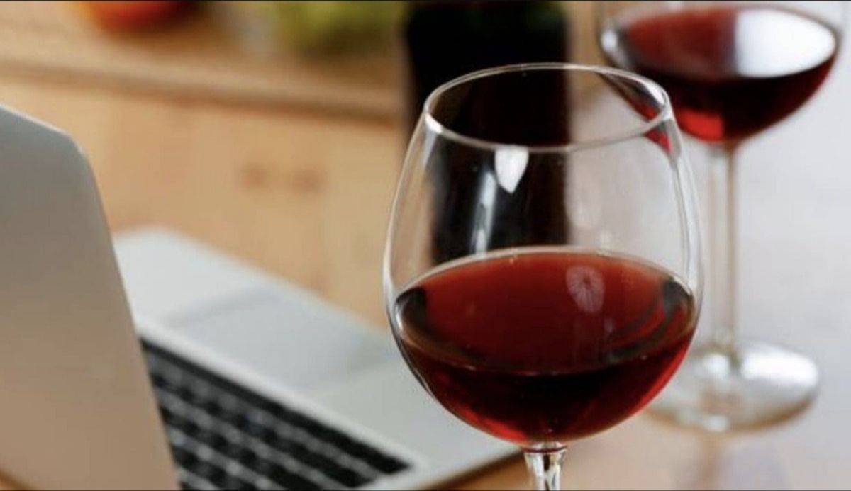 Glas rode wijn naast een laptop tijdens een online wijncursus