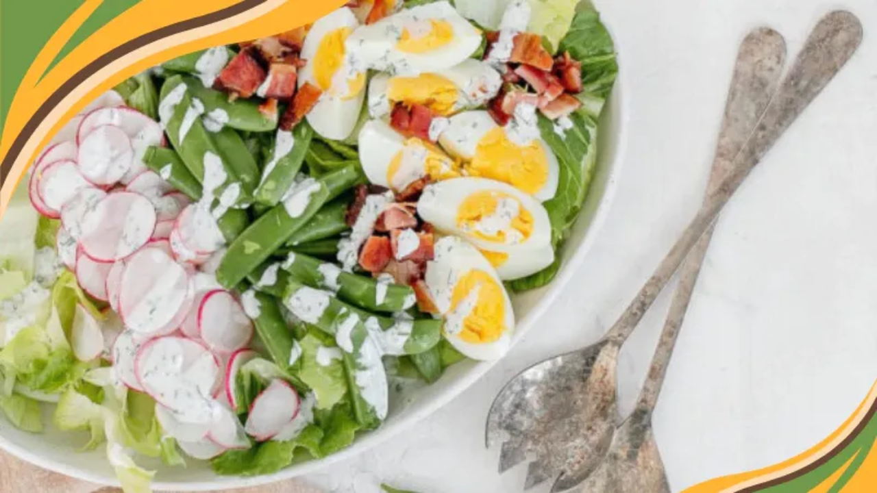 Cobb-style salad with lettuce, sliced radishes, snap peas, hard-boiled eggs, diced bacon, and creamy dressing in a white bowl beside rustic serving spoons, framed with decorative green and orange wave borders.