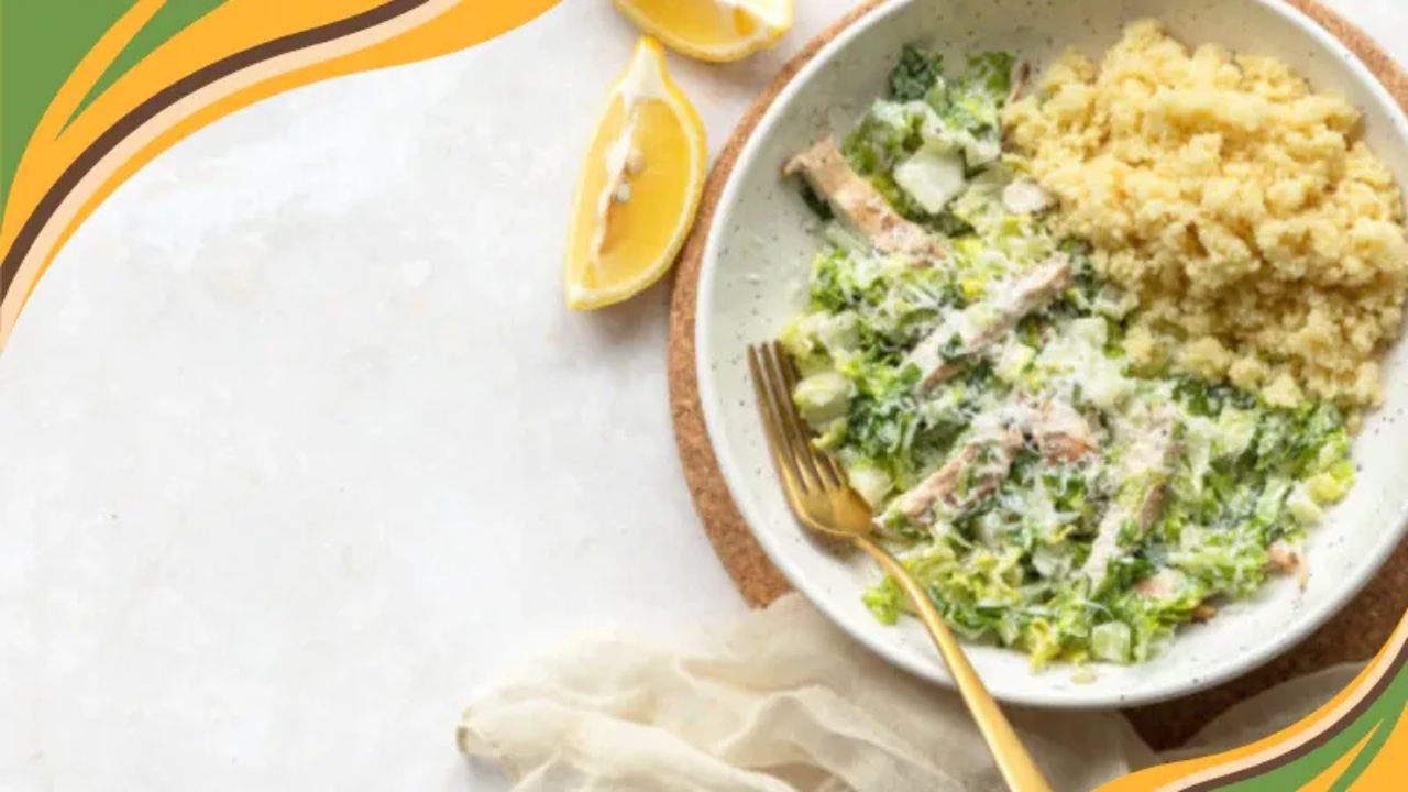 Creamy grilled chicken Caesar salad with couscous served in a bowl with a gold fork on the side.