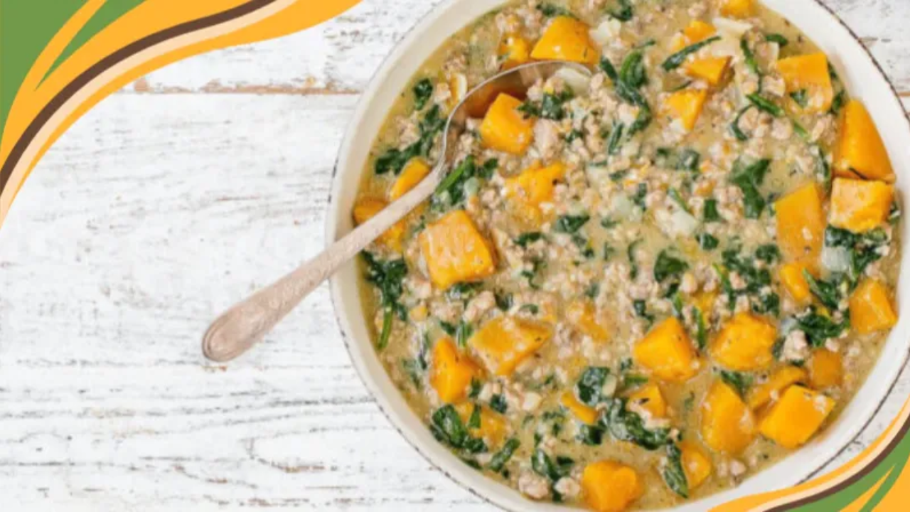 Hearty sausage, kale, and butternut squash stew served in a rustic bowl on a wooden table.