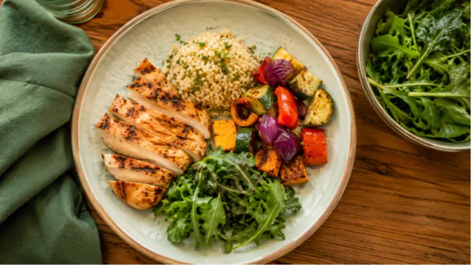 A simple, colorful plate of grilled chicken, roasted vegetables, and rice styled from above on a wooden table. This image represents the real, unrestrictive food choices at the heart of a sustainable weight loss lifestyle for women over 50.