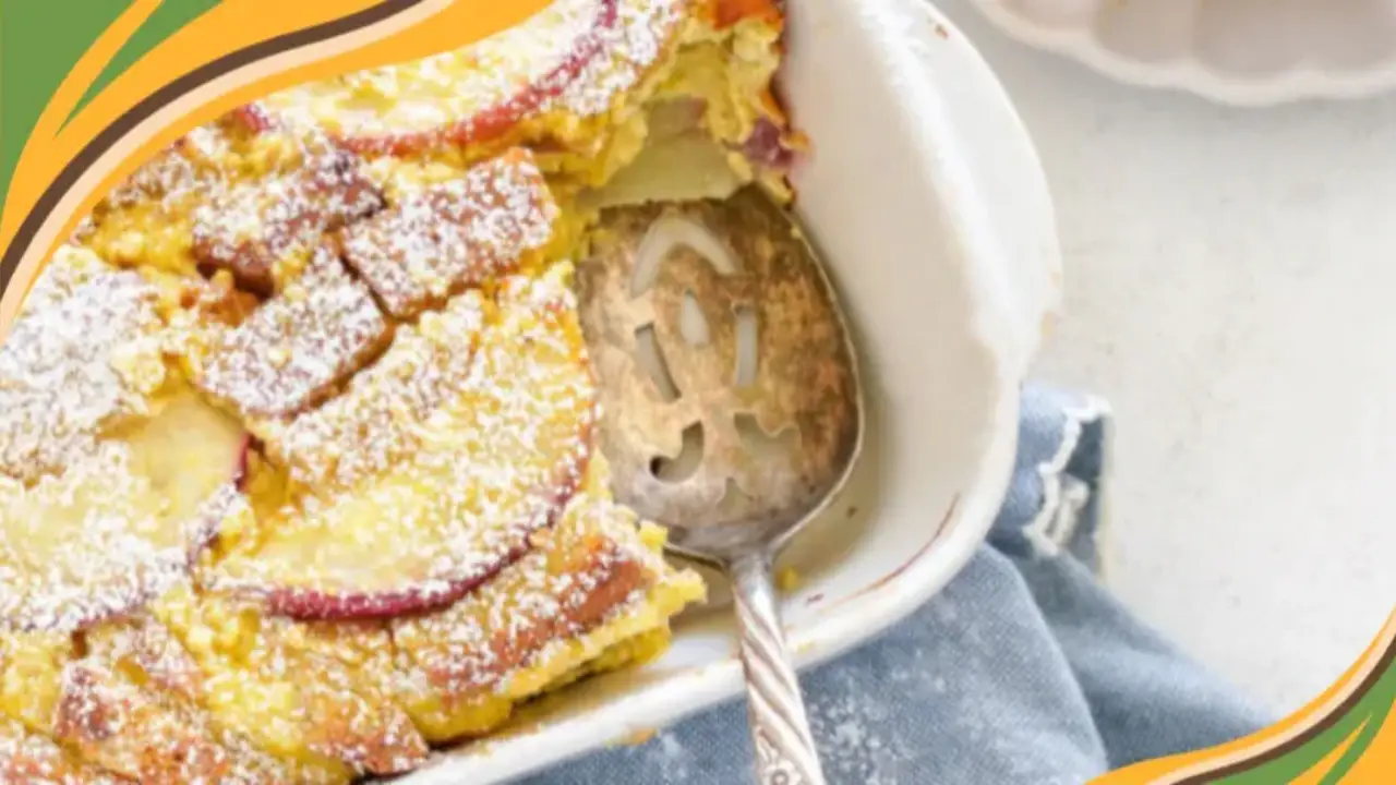 Delicious apple clafoutis dusted with powdered sugar in a white baking dish, perfect for a cozy dessert.