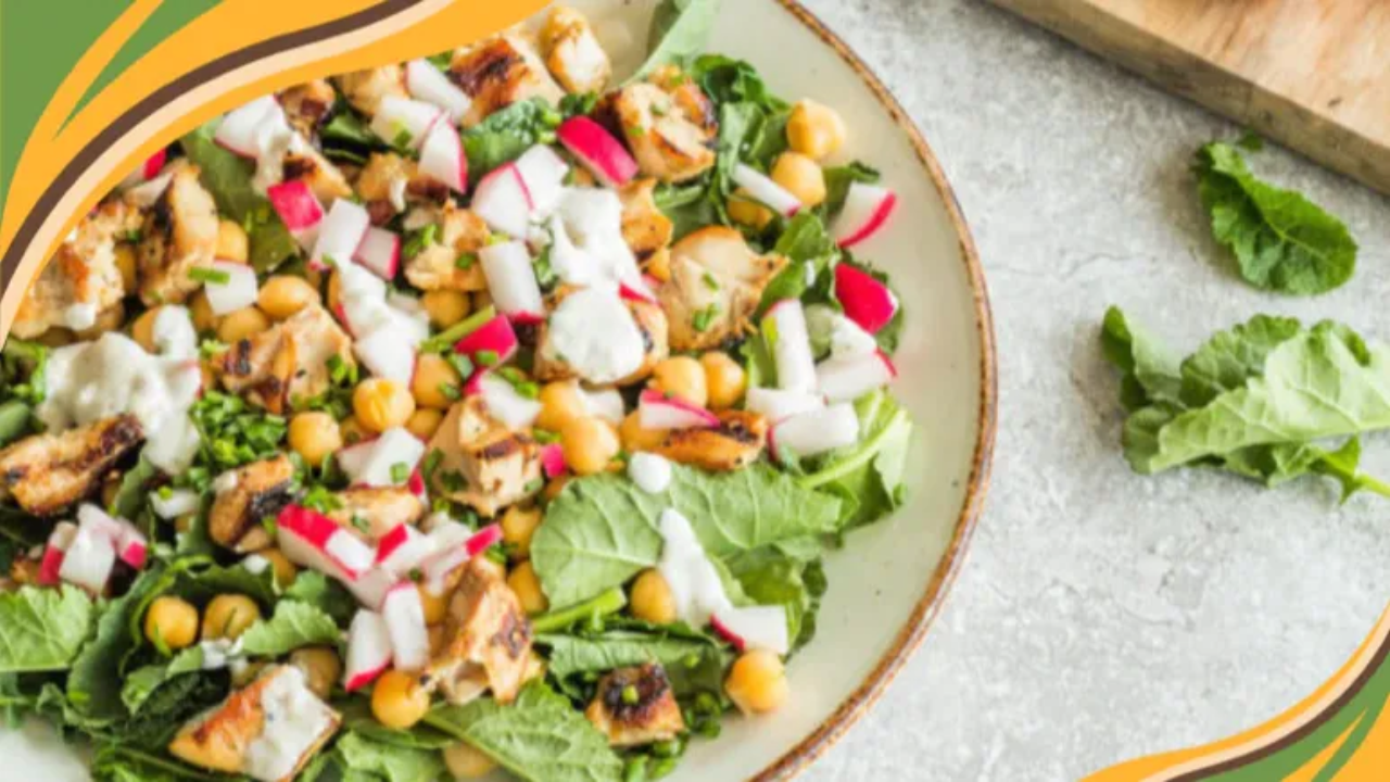 Grilled chicken salad with chickpeas, radishes, and creamy dressing on a bed of fresh kale leaves.