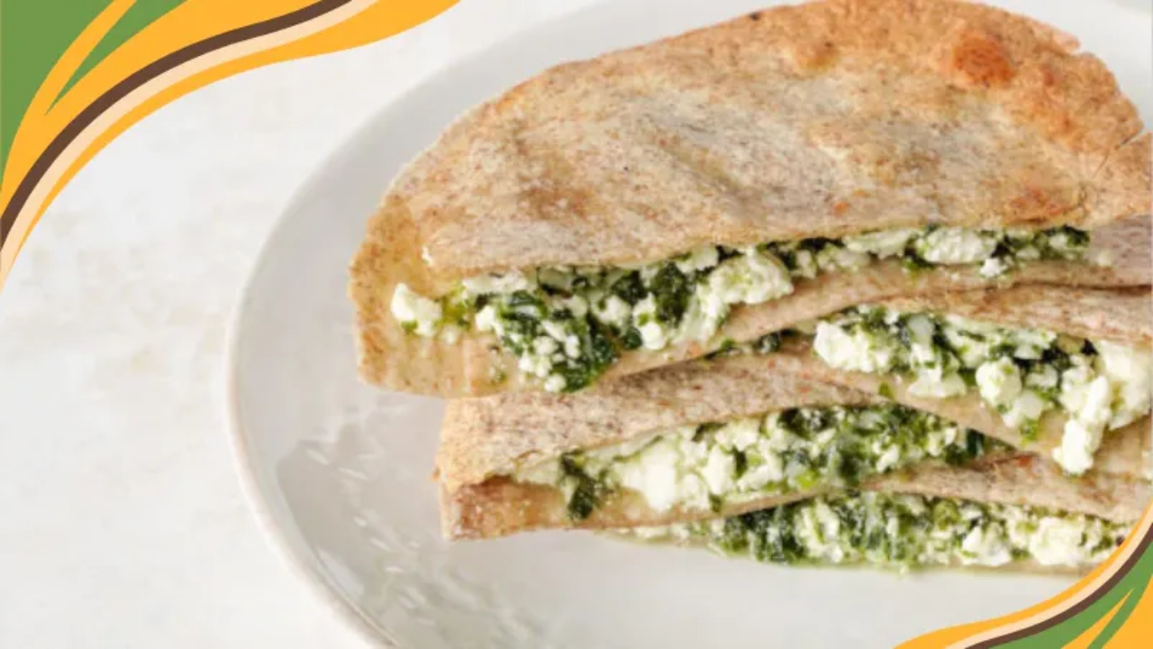 feta and spinach quesadilla cut in half on a white plate