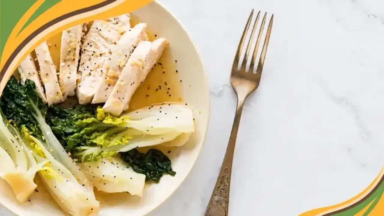 Sliced cooked chicken breast served with steamed leafy greens on a beige plate next to a vintage fork.