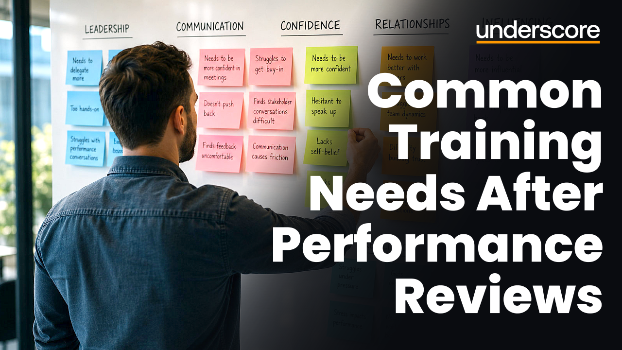 Professional viewed from behind grouping colourful notes into categories on a board, representing the identification of common training themes from performance review feedback.