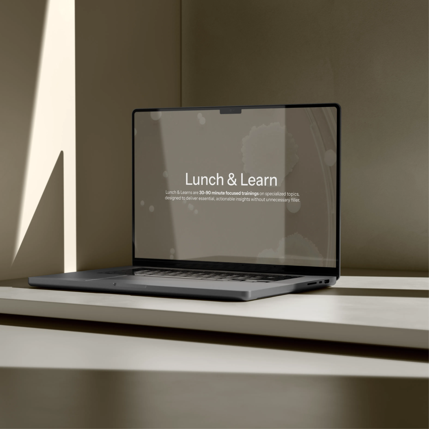 Laptop sitting on a table showing the Lunch & Learn graphic