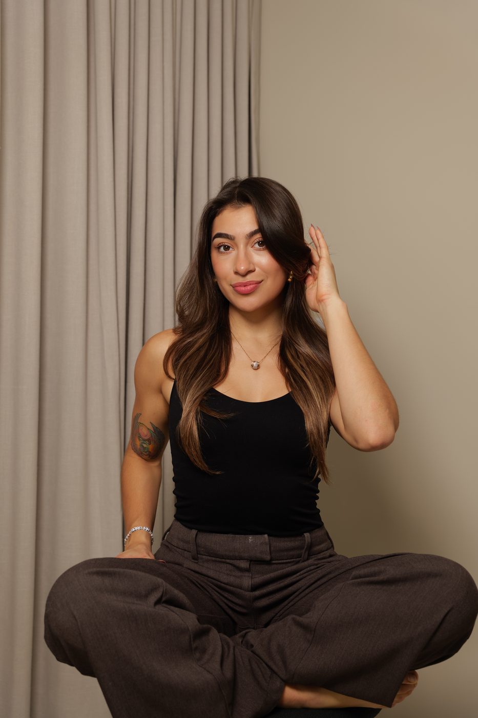 Katy Garcia, People Pleasing Coach, smiling and seated in a black tank top