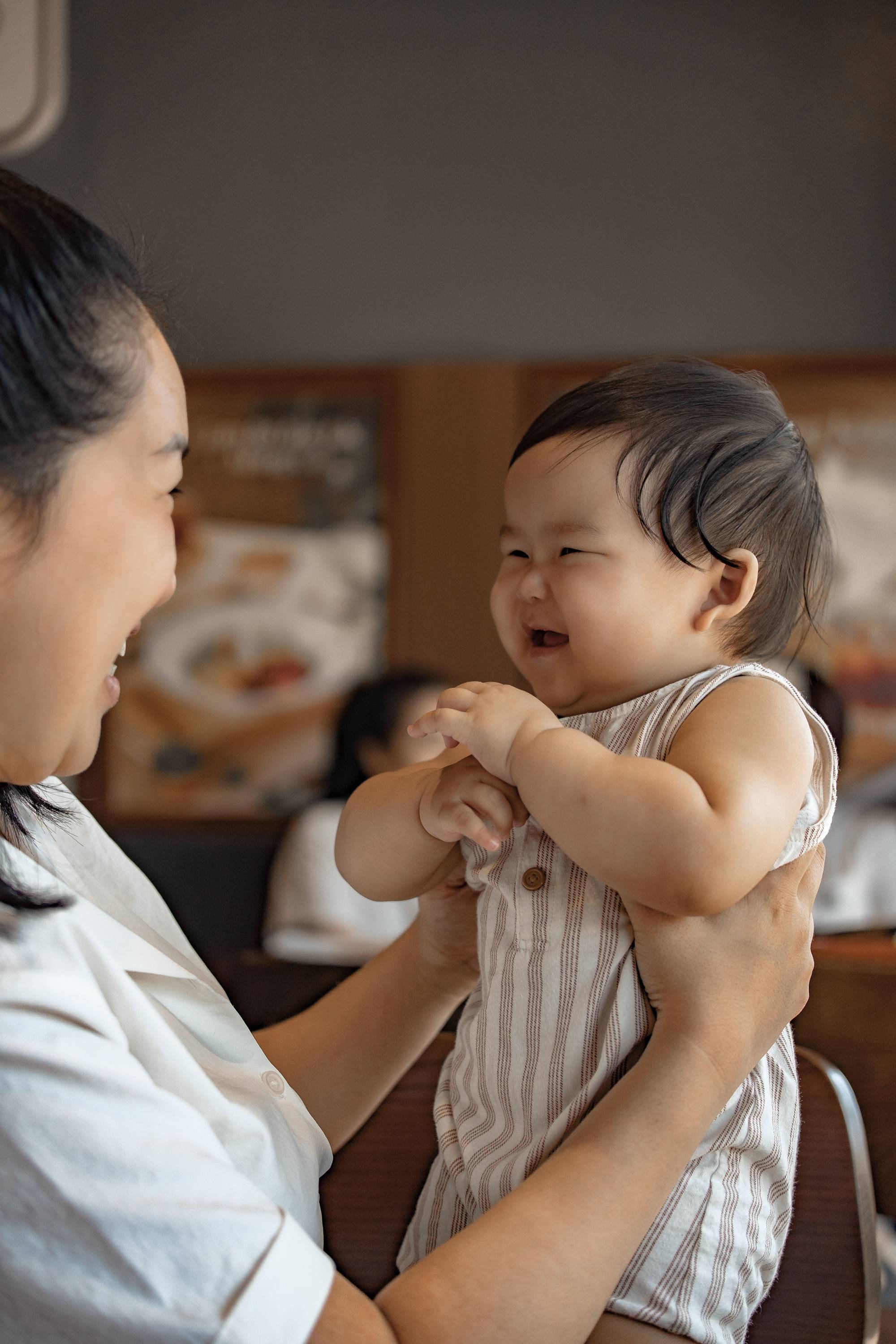 A parent holding a laughing baby in daylight