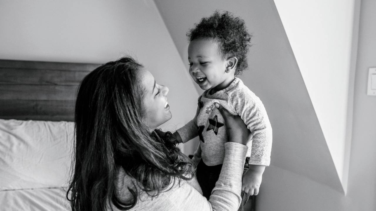 A mother smiling with her laughing toddler