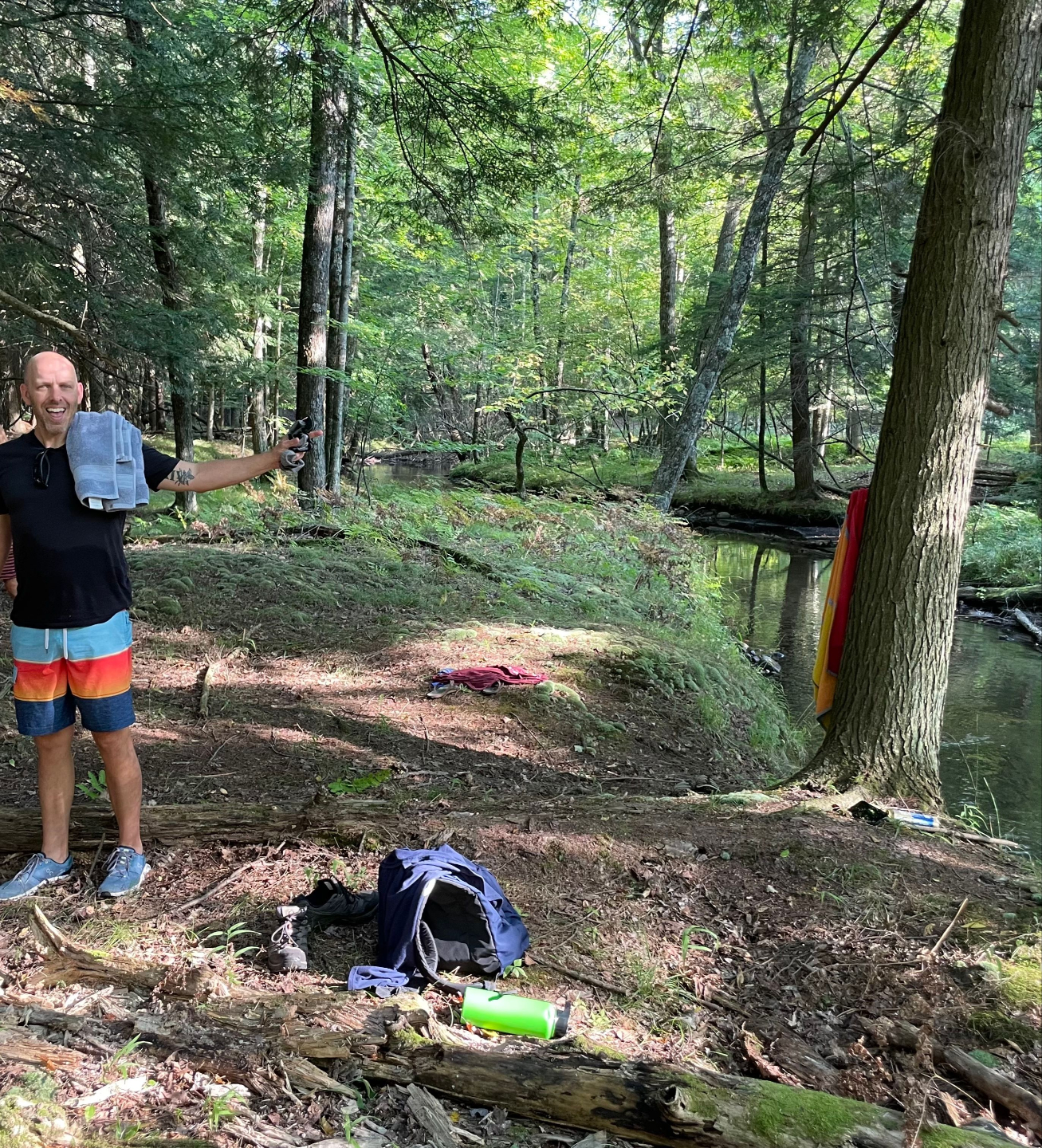 Man standing near a calm river at dusk surrounded by northern Michigan forest near Lynx Run Wilderness Retreat