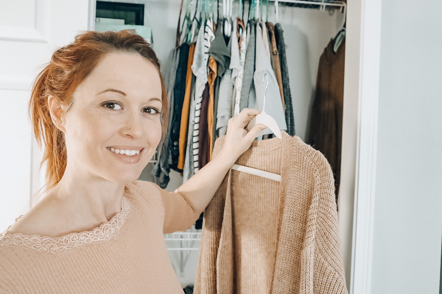 Mia holding a favorite sweater in front of her minimalist closet