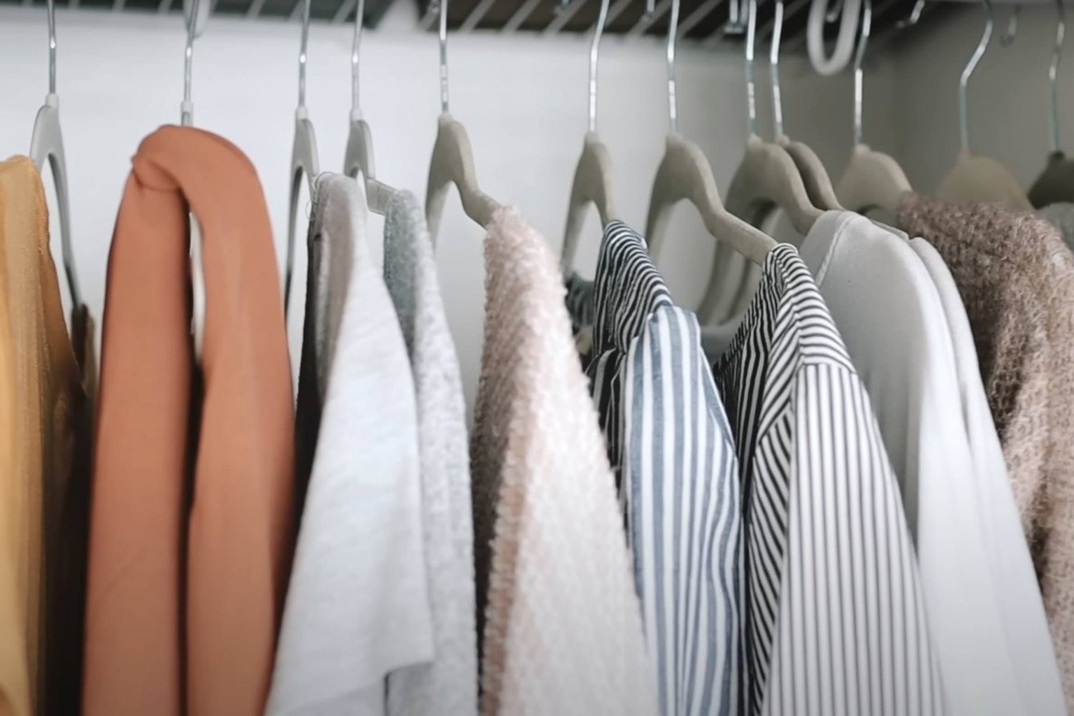 A row of coordinating tops on matching hangers in a simple closet