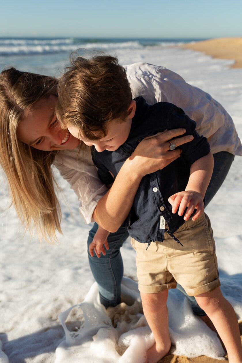 A parent leaning in close to their child at the beach