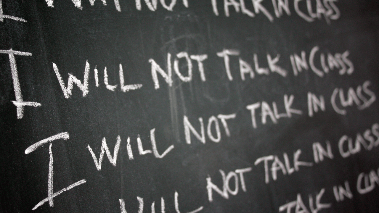 "I will not talk in class" written on a chalkboard over and over