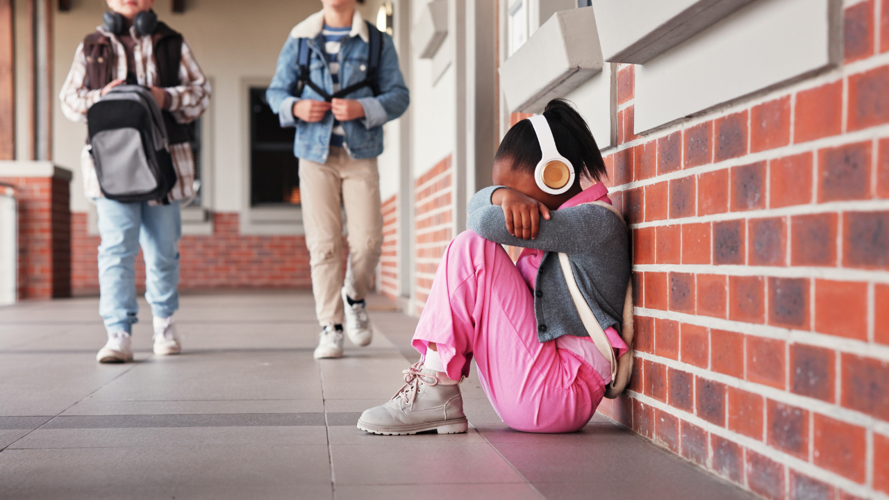 Girl in headphones sitting alone on hallway floor