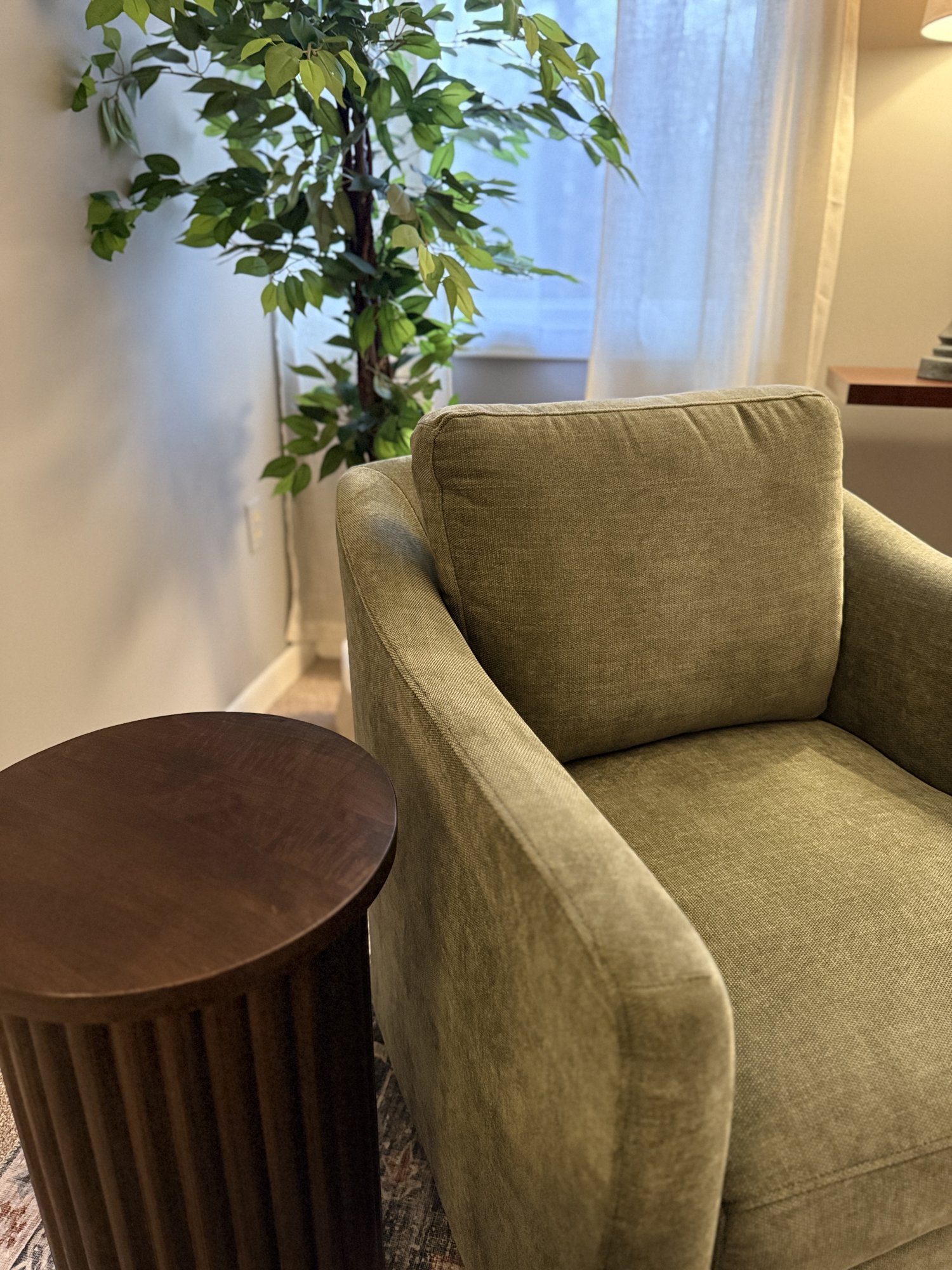 A green armchair and side table in Kristen's therapy office