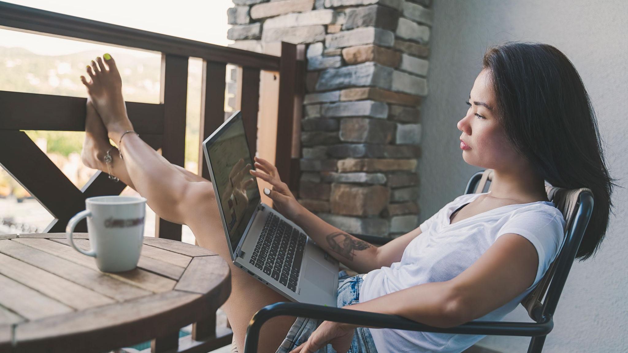Remote work setup with a laptop and coffee overlooking a scenic town, illustrating the freedom and flexibility of working as a virtual assistant from anywhere.