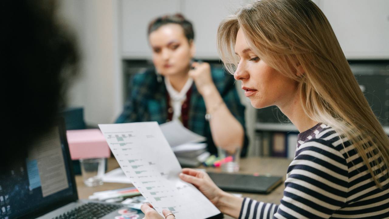 marketing manager reviewing campaign plans with a creative team at a shared desk in a modern office
