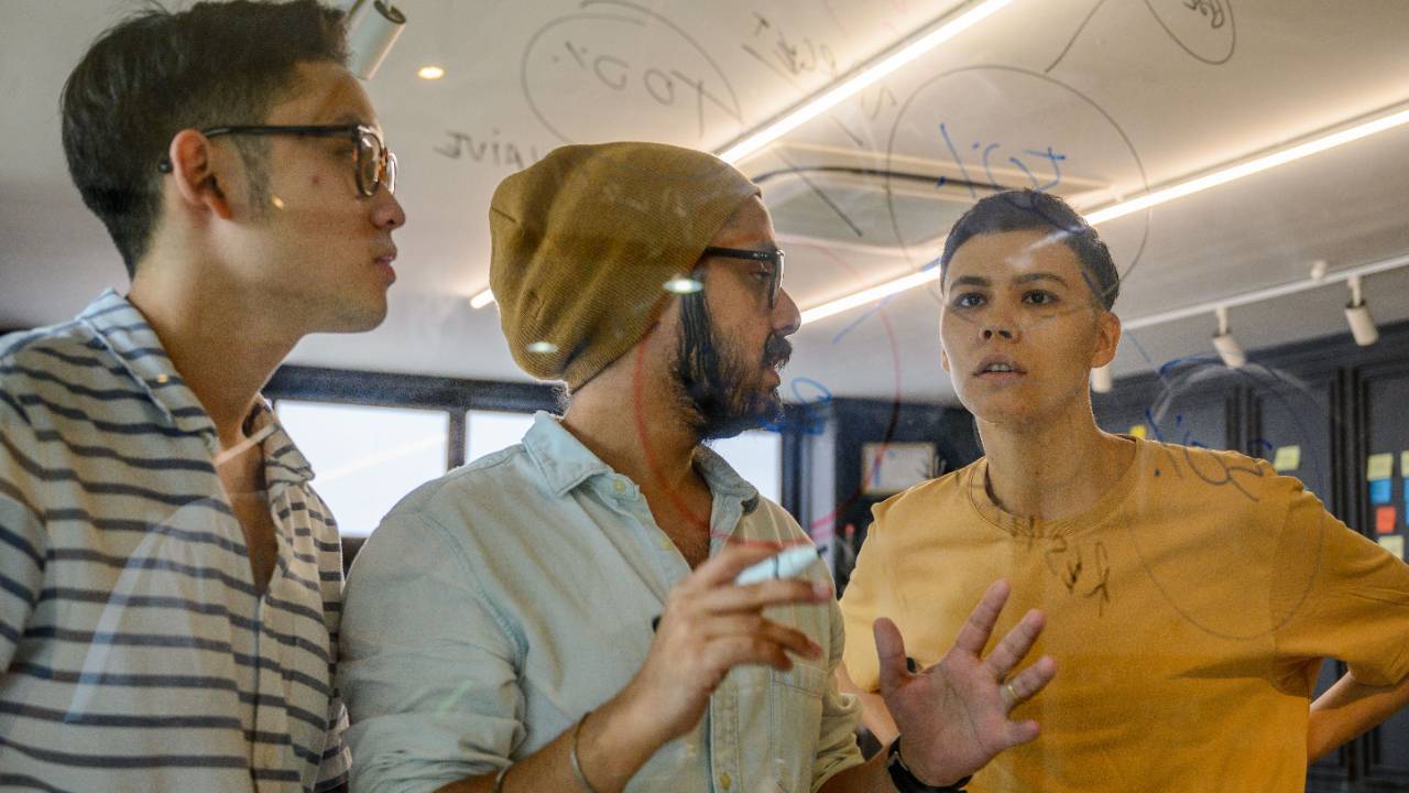 creative team lead reviewing project workload board with designers in a modern studio office