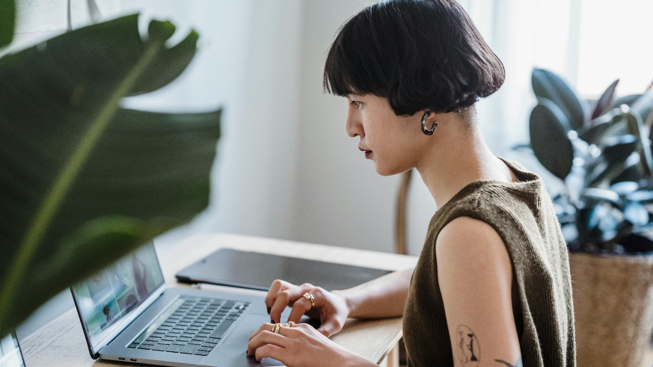Creative project manager studying certification materials on a laptop in a bright modern studio workspace