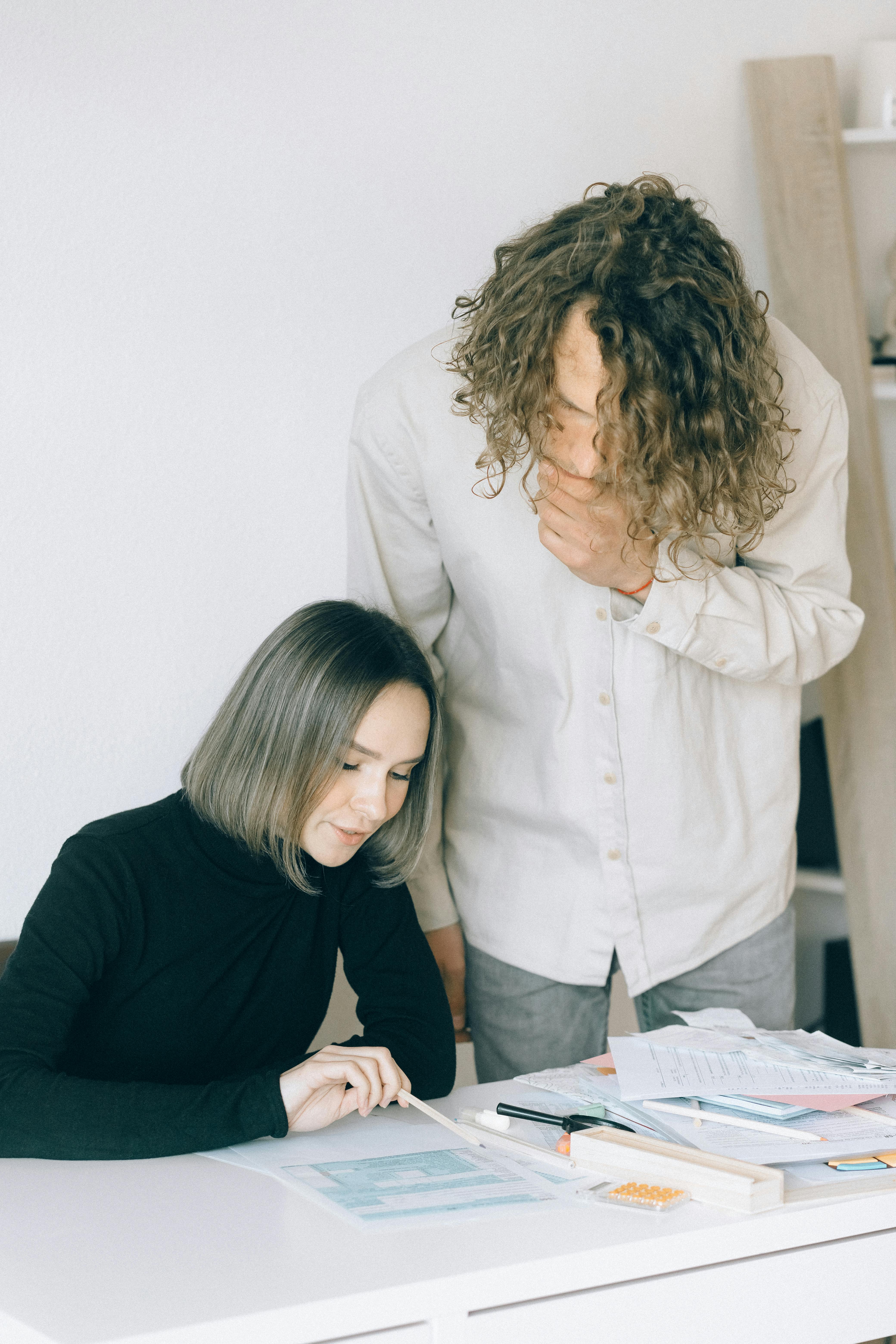 creative project manager and client sitting together reviewing a printed document at a bright office desk with notebooks and coffee