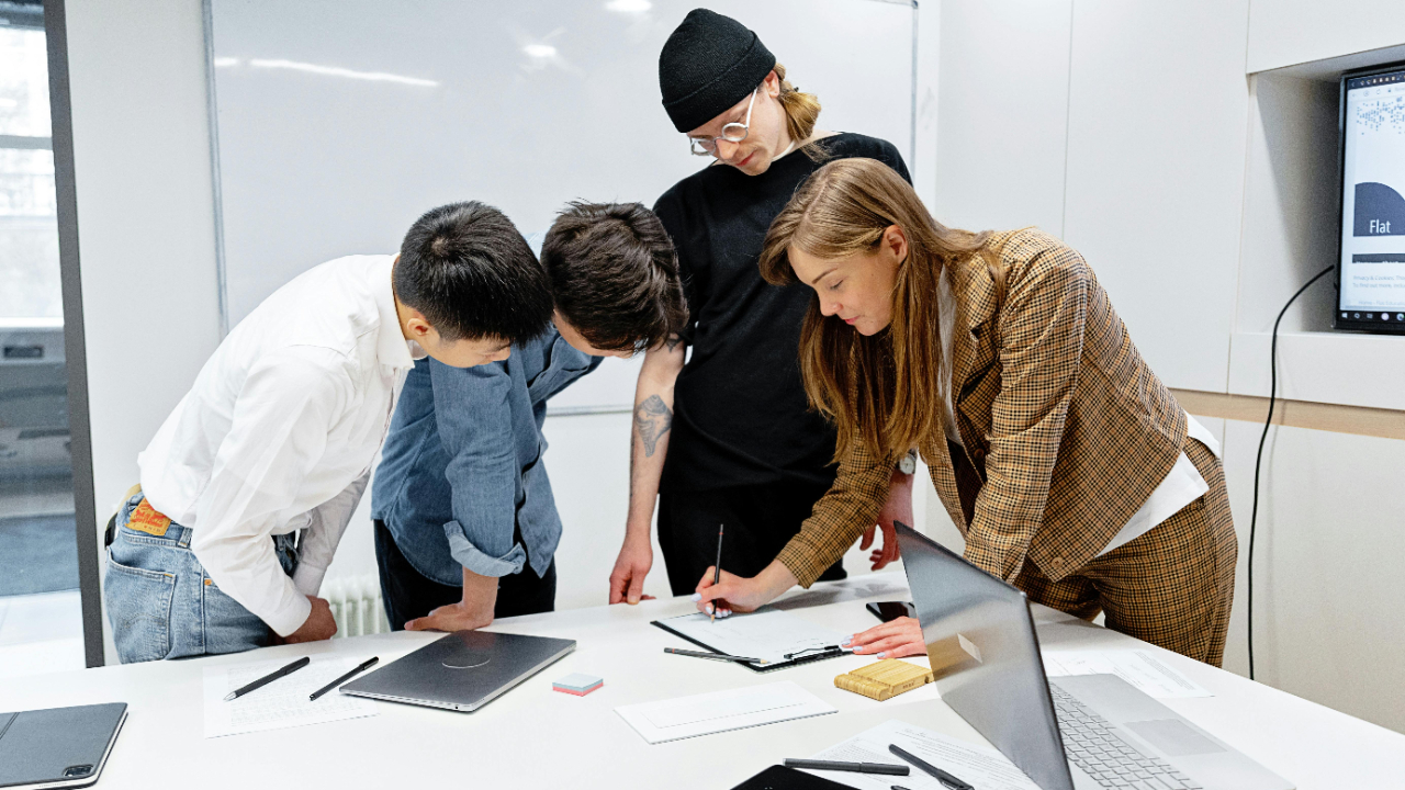 In-house creative team reviewing project plans and design work at a conference table with laptops in a bright modern corporate office