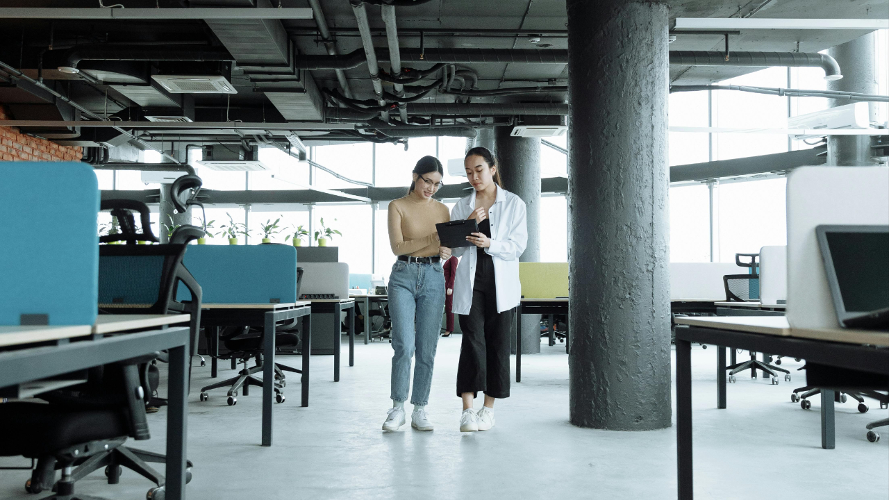 account manager reviewing client materials and project plans at a desk with laptop in a bright modern advertising agency office