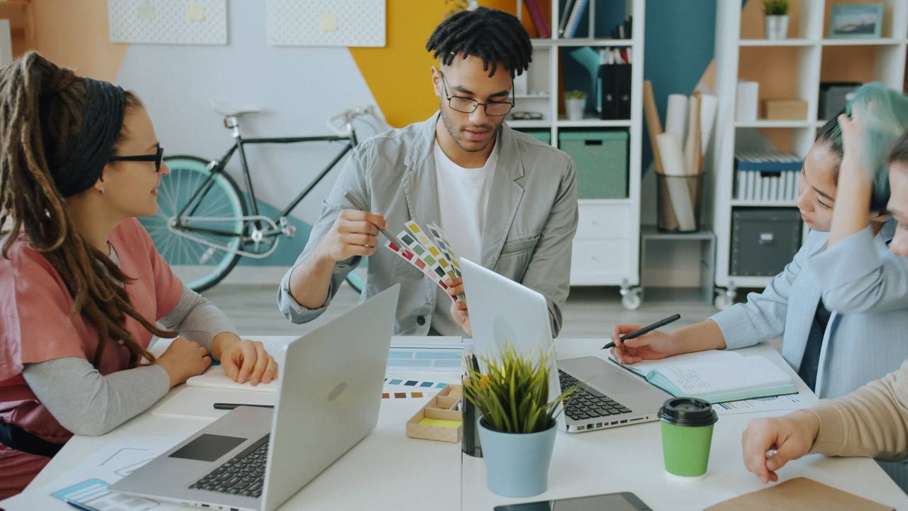 Creative team reviewing color swatches at a table in an agency workspace, faces visible.