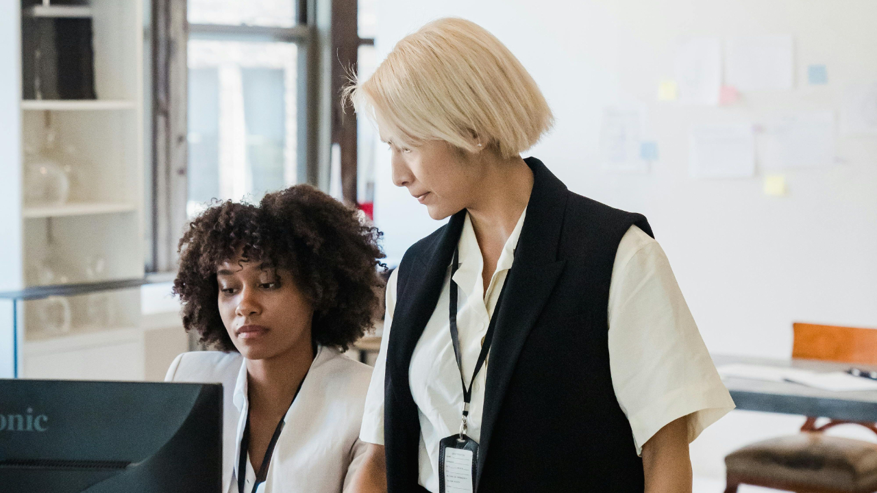 Frustrated creative team member at desk with multiple monitors and scattered notes in a busy modern office working late