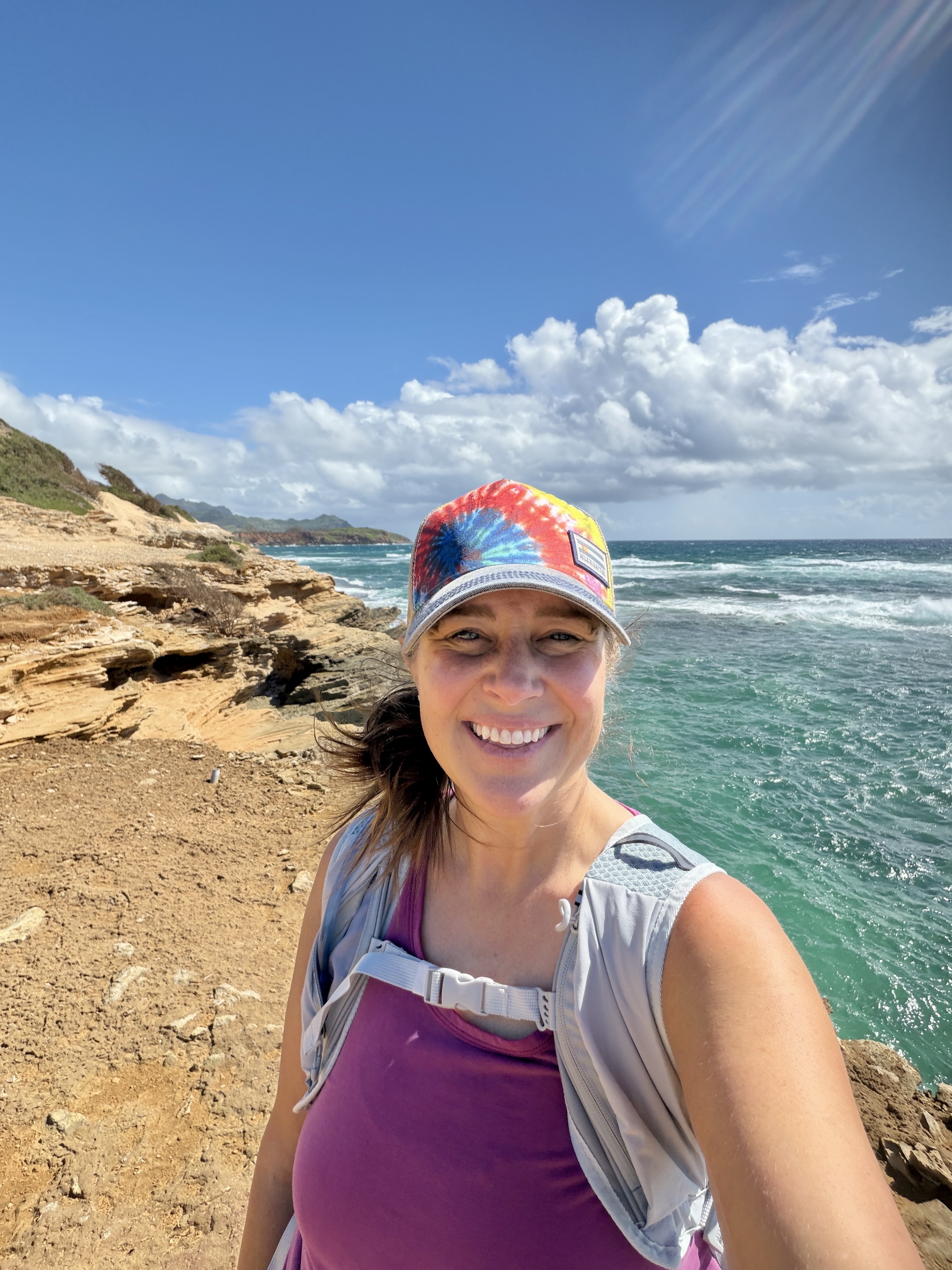 Kara on a coastal hike in a tie-dye hat