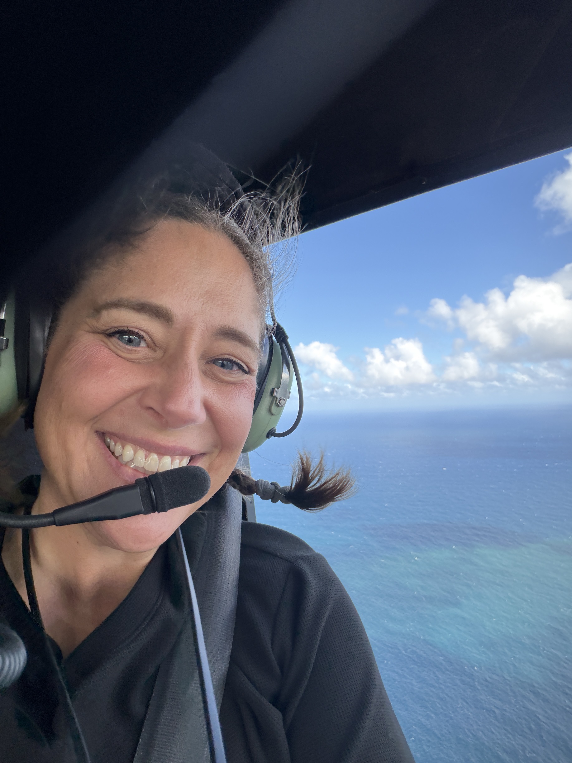Kara smiling in a helicopter over the ocean