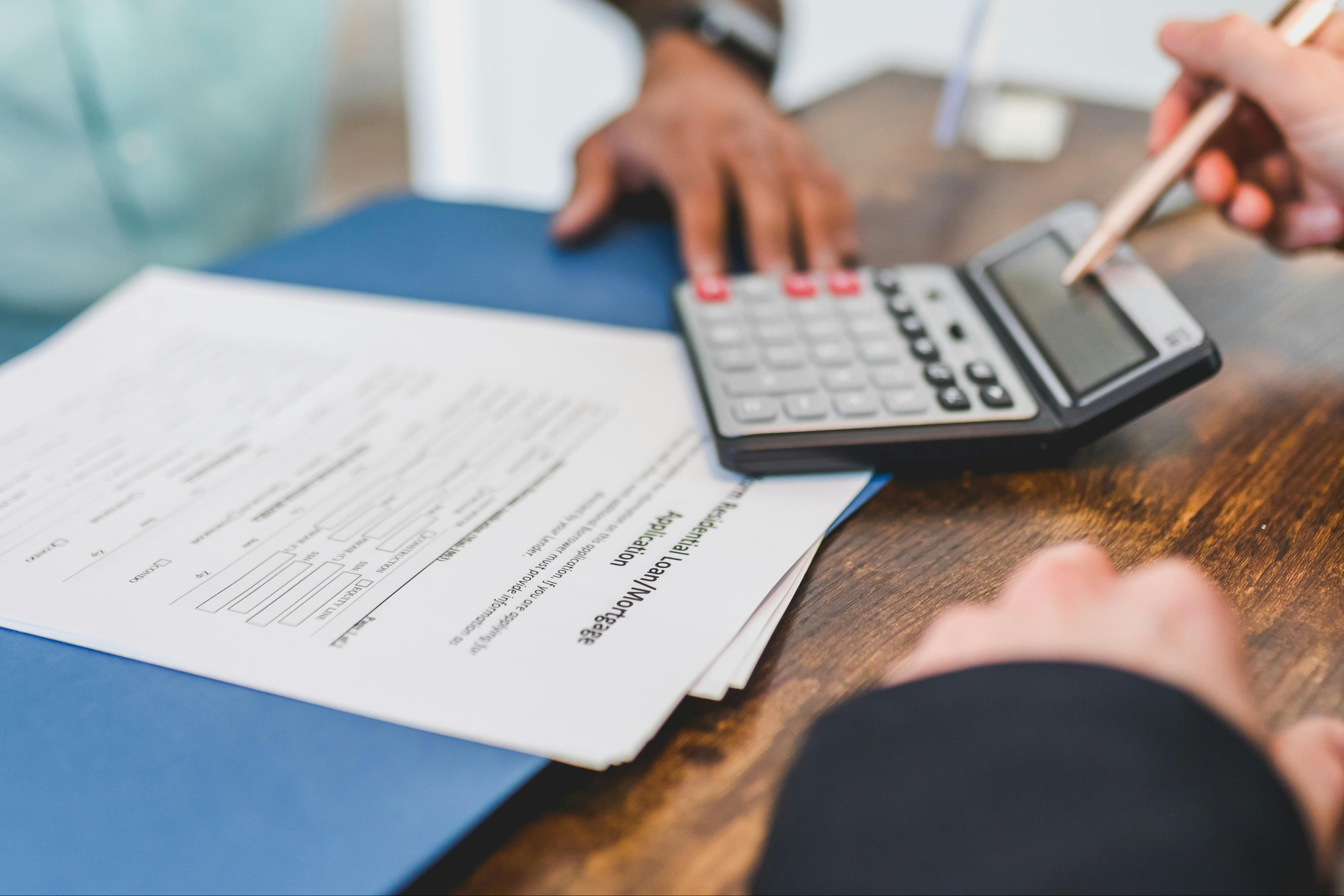 Legal professional and client discussing documents at a table, with a calculator and legal paperwork visible