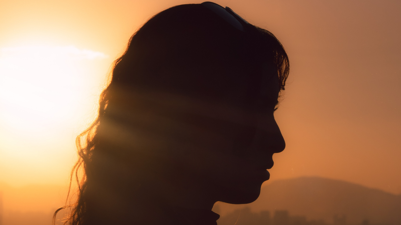 Silhouette profile of a woman against warm sunset light, representing breath, embodied awareness, presence, and returning to Ground in Cube Philosophy.