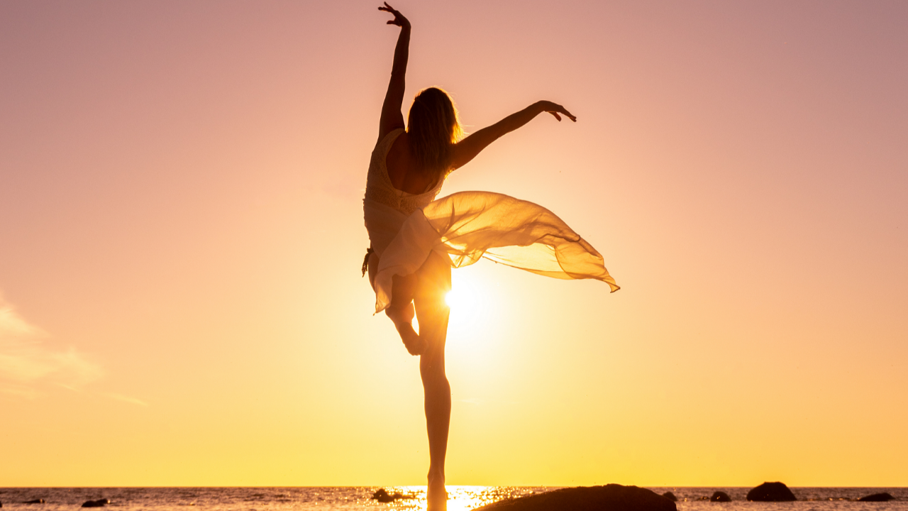 Silhouette of a woman balancing in a dance pose against golden sunlight, representing repetition, embodied learning, balance, correction, and practiced orientation in Cube Philosophy.