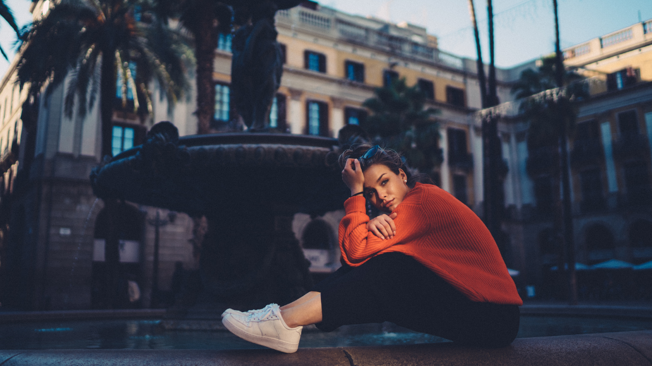 A reflective woman sits alone beside a fountain, symbolizing the experience of feeling lost despite intelligence, insight, and the ability to see many possibilities. Inspired by the Cube Philosophy article Why Smart People Feel Lost.