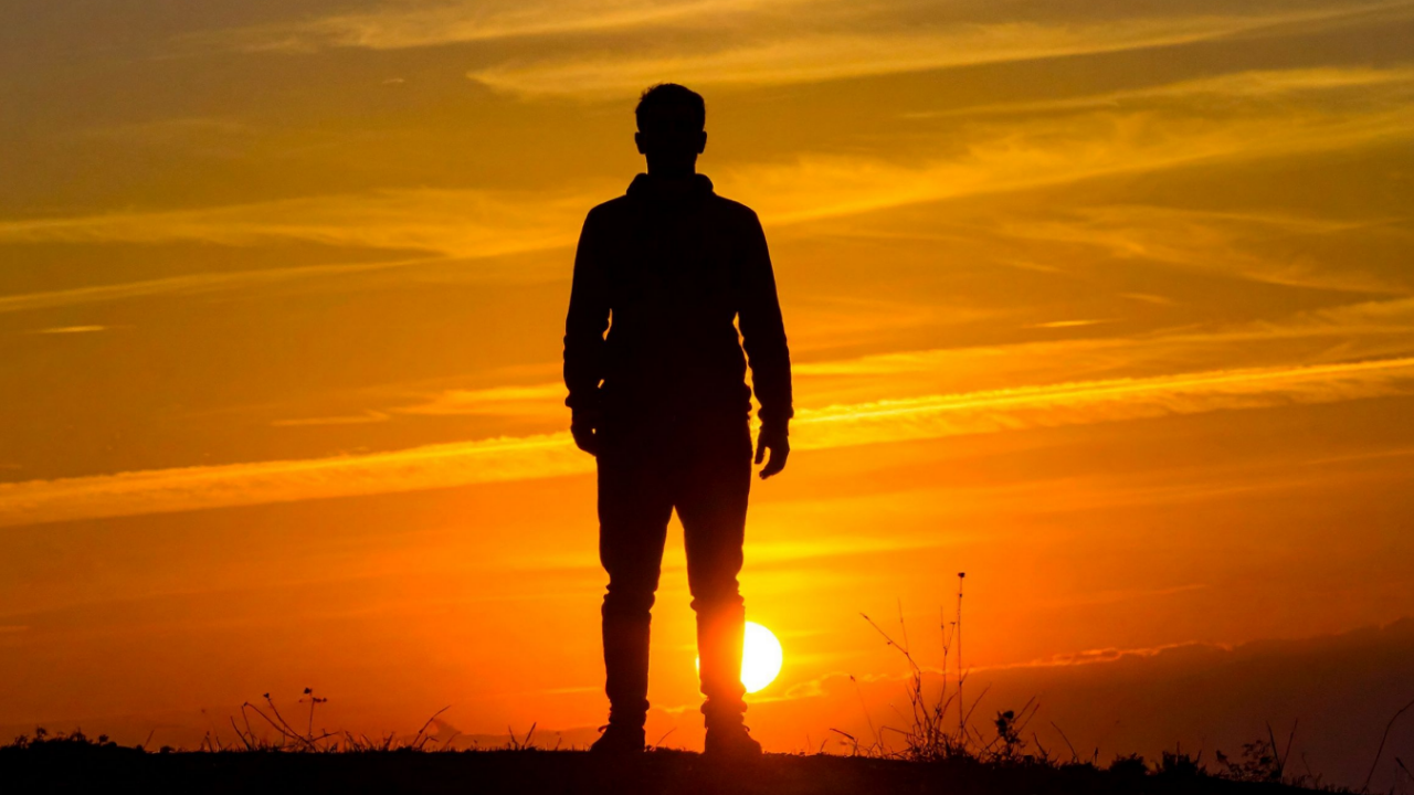 Silhouette of a person standing against a glowing sunset, representing bodily sensation, awareness, Ground, and discernment in Cube Philosophy.
