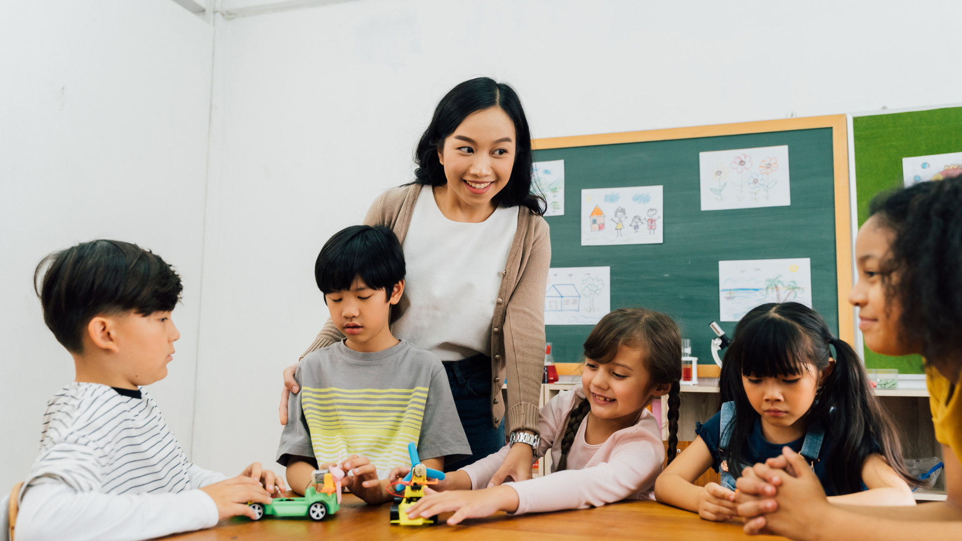 A teacher and five students working together at a classroom table